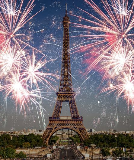 Der Eiffelturm in Paris, umgeben von einem großen, funkelnden Feuerwerk am Nachthimmel über der Stadt.